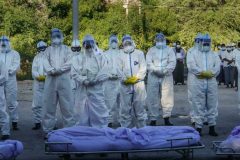 Volunteers praying in front of those who died from Covid End of Covid pandemic in sight: WHO